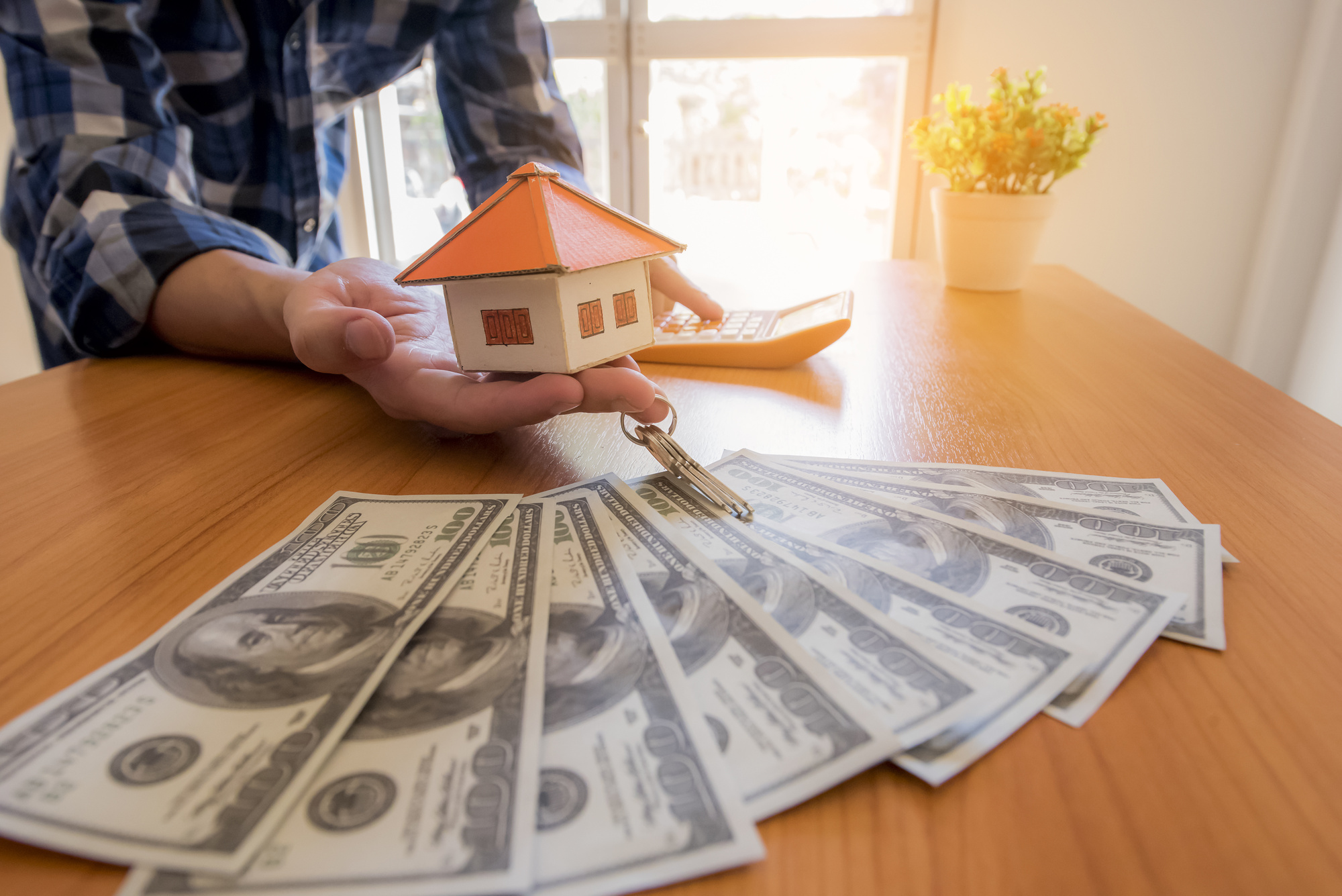 person holding house with cash on table